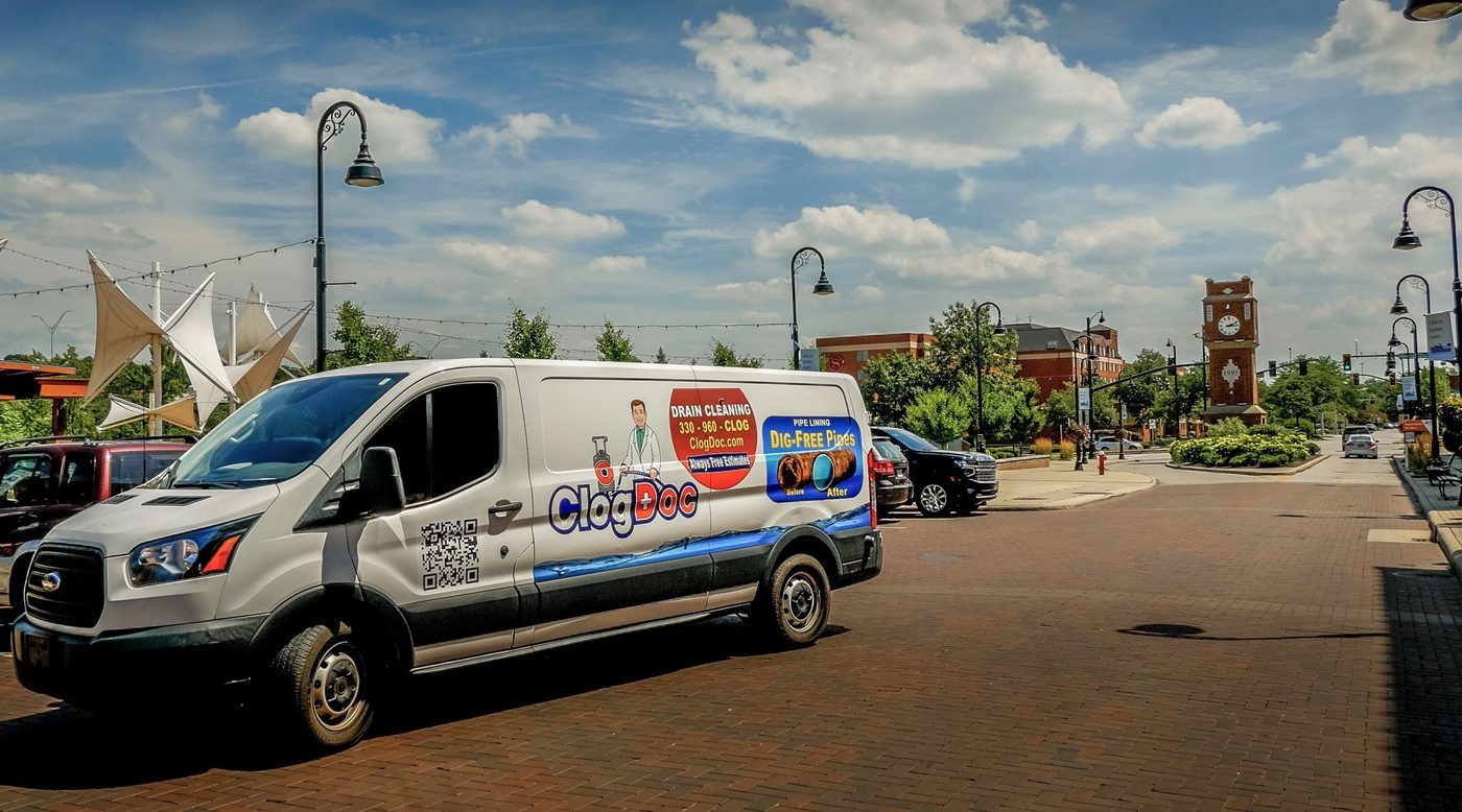 Clog Doc van on the brick street in downtown Cuyahoga Falls, clock tower behind it